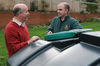 Man and OFTEC technician standing in rural garden by a liquid fuel tank