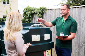 OFTEC technician pointing at liquid fuel tank and talking to homeowner 